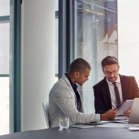 Tablet, laptop and business men planning in conference room meeting, teamwork and discussion of corporate data. Professional people or partner talking, review or report analysis on digital technology.